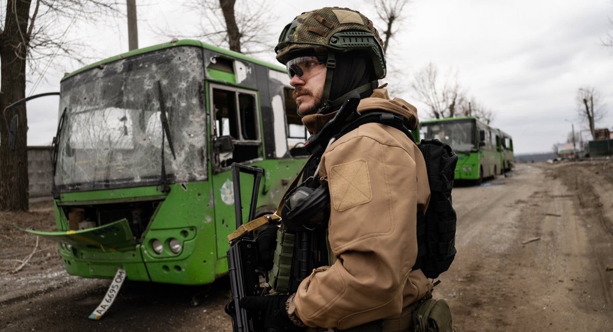 Український воїн на тлі автобусів, що мали забезпечити евакуацію мирних громадян